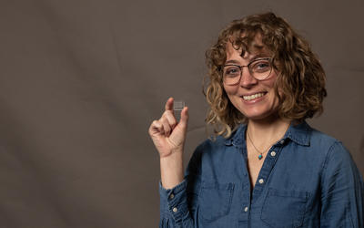 Aly Artusio-Glimpse smiles and holds up a tiny glass square.